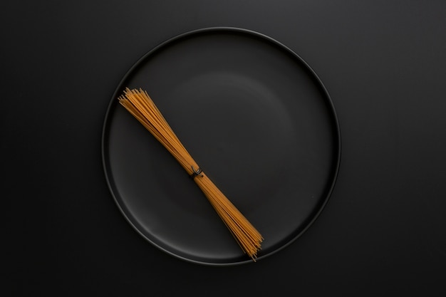 Dark background with dark plate with pasta