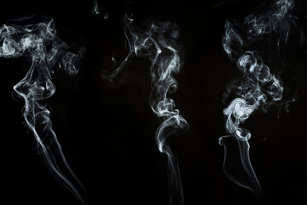 Dark background with three wavy forms of smoke
