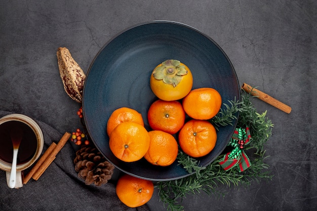 Free photo dark blue plate with persimmon and tangerines