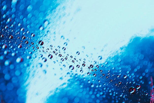 Dark blue water drops background on glass