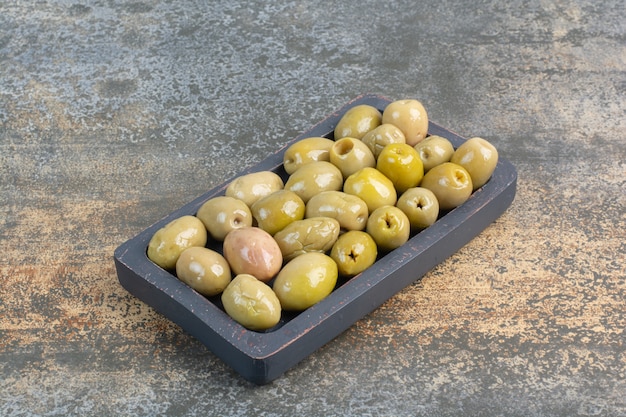 Free photo a dark board of some salty delicious olives on marble background