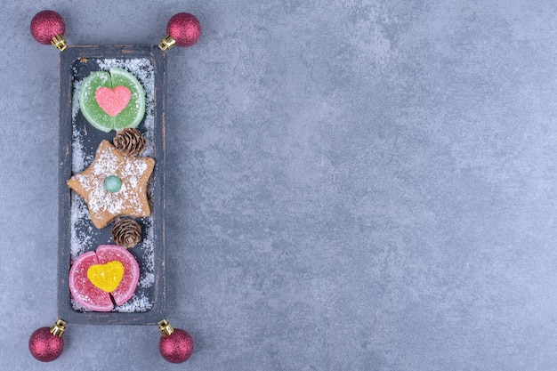 Foto gratuita una tavola scura con stella di biscotti e caramelle di gelatina zuccherate