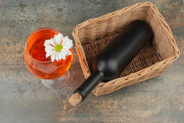 Dark bottle on basket with glass of juice on marble background. High quality photo