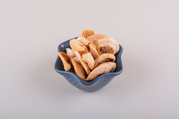 Dark bowl of dry apple rings placed on white table. High quality photo