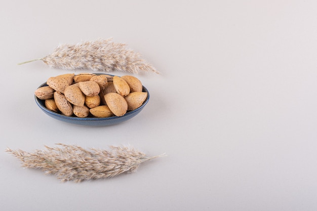 Dark bowl of shelled organic almonds on white background. High quality photo