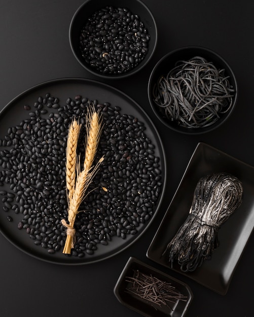 Dark bowls with pasta and beans on a black background