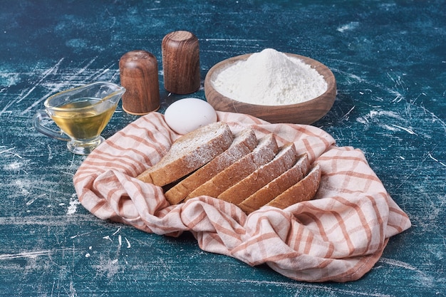 Dark bread slices with ingredients on blue table.