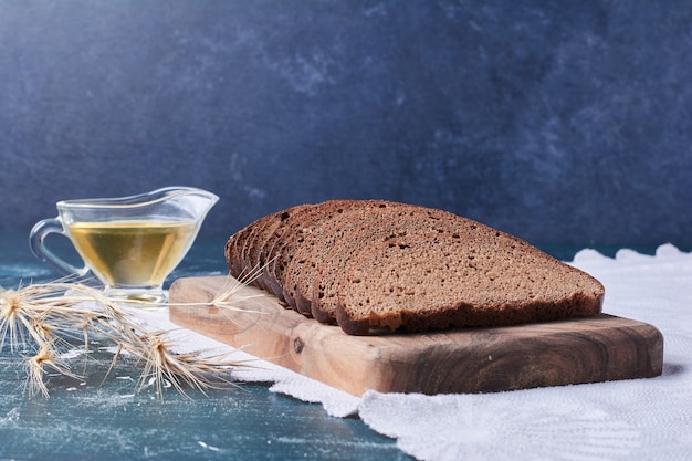 Dark bread slices with oil on blue table.