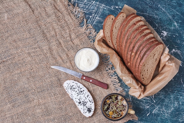 Dark bread slices on wooden tray with toast and drink.