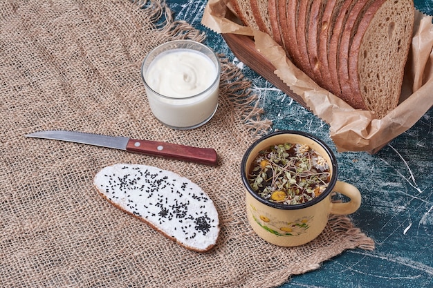 Dark bread in a wooden tray with a slice of toast and drink.