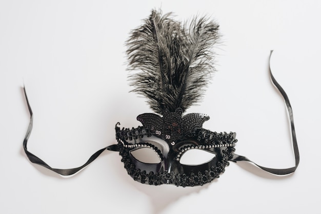 Free photo dark carnival mask with feather on light table