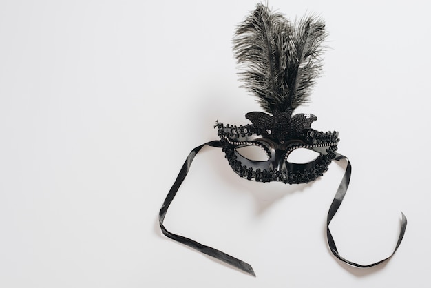 Dark carnival mask with feather on table