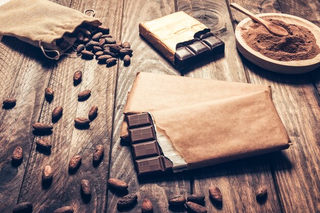 Dark chocolate bars with cocoa beans on wooden background