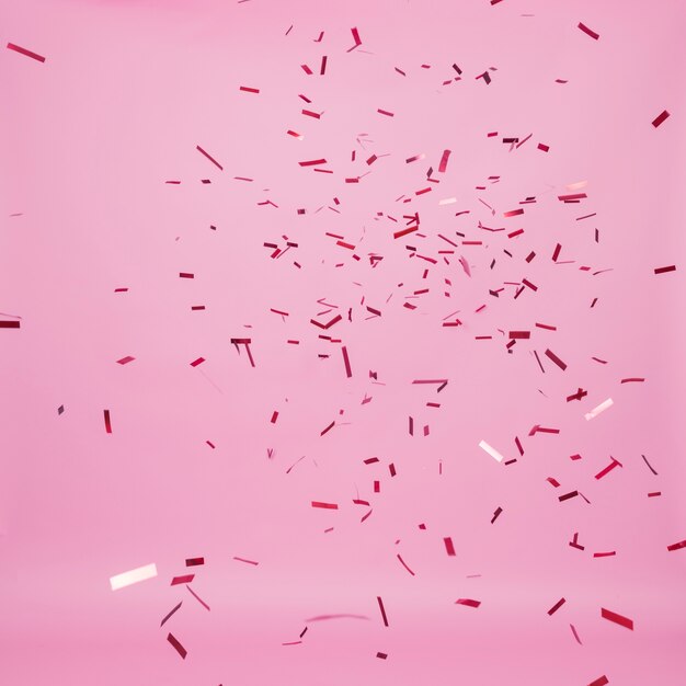 Dark confetti falling on pink background