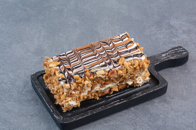 A dark cutting board of sweet cake on gray table.