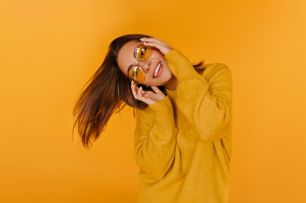 Dark-eyed refined girl laughing . Winsome european lady dancing with pleasure on yellow wall.