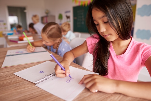 Foto gratuita ragazza capelli scuri disegno in classe