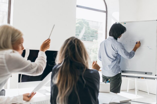 Dark-haired man drawing infographic on flipchart standing in conference hall