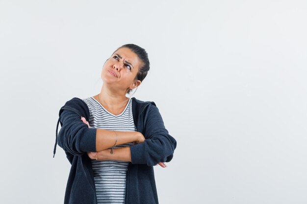 Foto gratuita donna dai capelli scuri che guarda lontano mantenendo le braccia incrociate in camicia