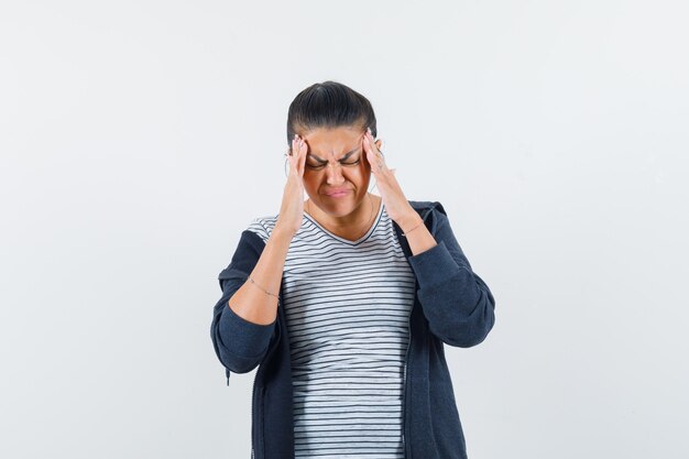 Dark-haired woman rubbing her temples in shirt