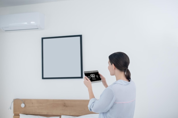 Dark-haired woman running a room air conditioner