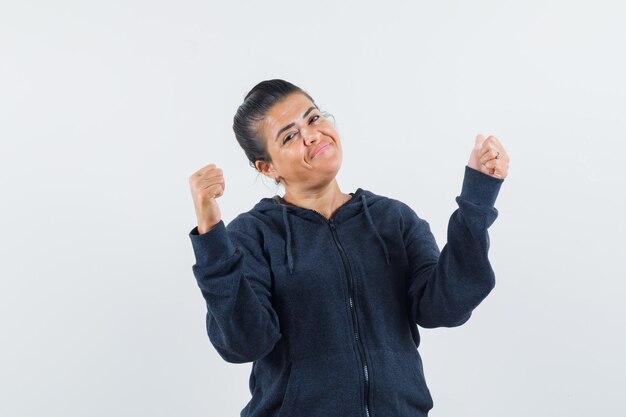 Dark-haired woman showing thumb up in jacket and looking optimistic 