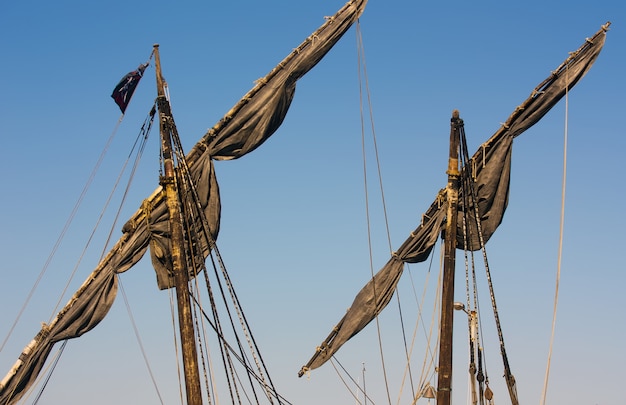 Dark masts of a ship with the sky in the background