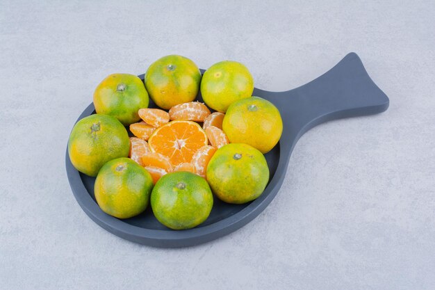 A dark pan of sour tangerines on white background. High quality photo