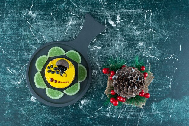 黄色の焼きたてのケーキと大きなクリスマスの松ぼっくりが入った暗い鍋。高品質の写真
