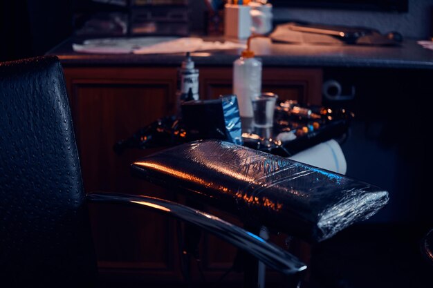 Dark photo of different equipment for tattoo making at tattoo salon.