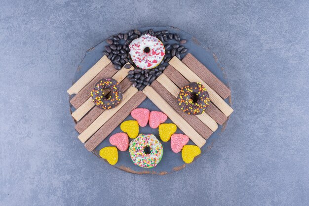 Free photo a dark plate full of donuts and heart shaped jelly candies