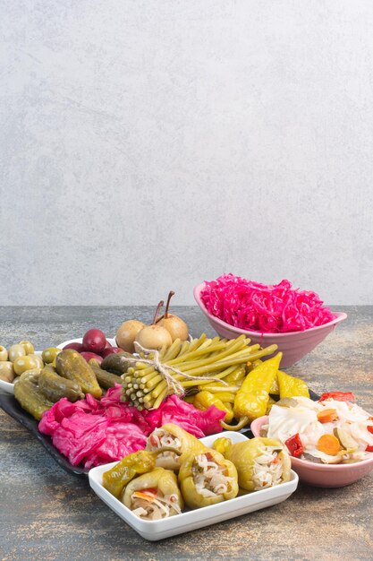 A dark plate full of pickled cucumbers and red salty cabbage on marble background. High quality photo