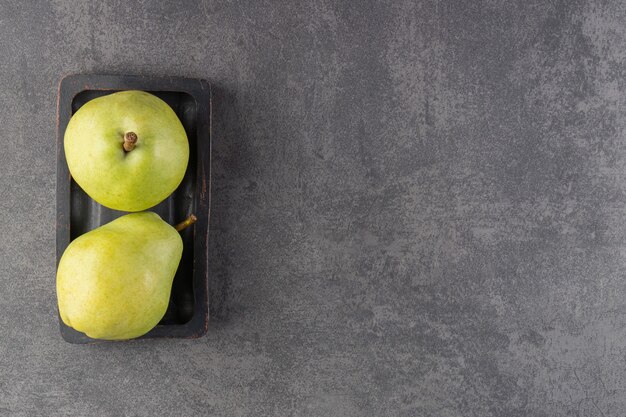 Dark plate of tasty green pears on stone surface