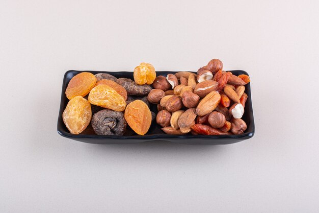 Dark plate of various organic nuts on white background. High quality photo