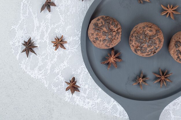 A dark plate with chocolate cookies with star anise