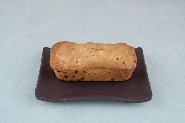 A dark plate with delicious fresh cake on white table.