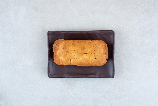 A dark plate with delicious fresh cake on white table.