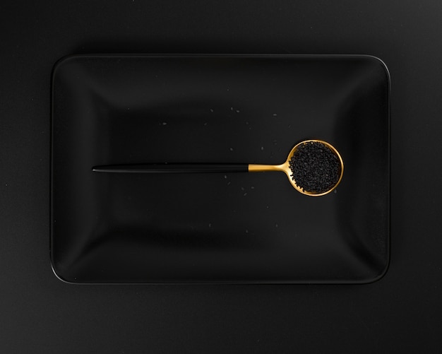 Dark plate with a spoon of poppy seeds on a dark background