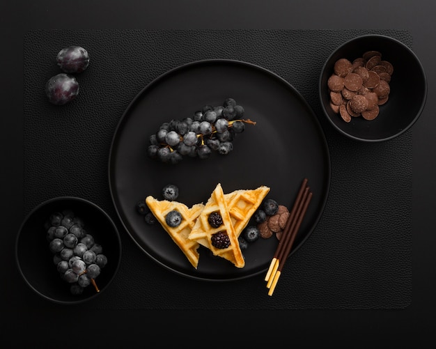 Dark plate with waffles and grapes on a dark background