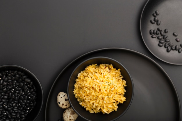 Dark plates with beans and bowl of rice on a dark table