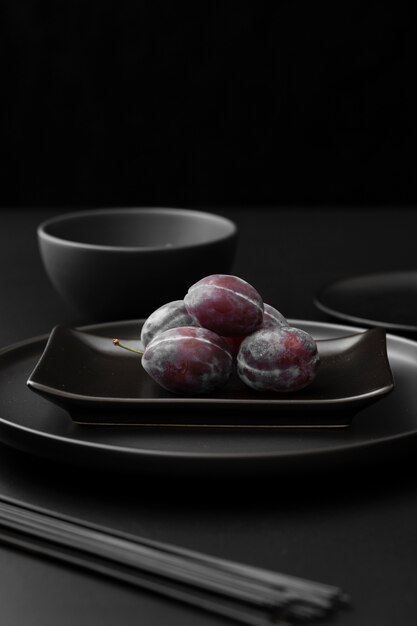 Dark plates with plums on a dark table