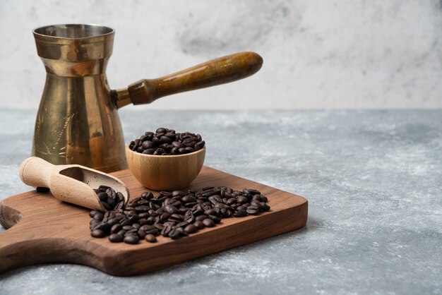 어두운 볶은 커피 원두와 나무 절단 보드에 커피 메이커.