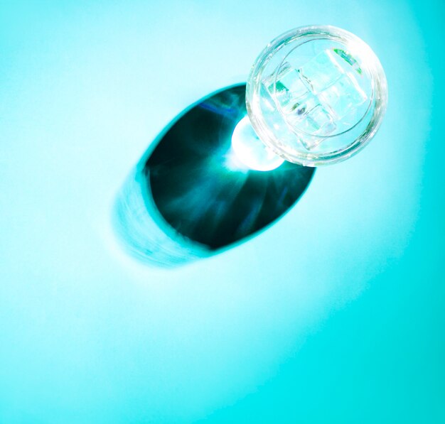 Dark shadow of transparent wine glass on turquoise background