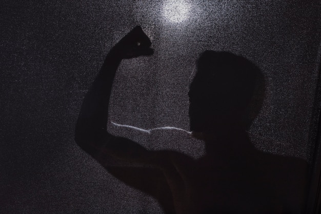 Dark silhouette of guy showing biceps