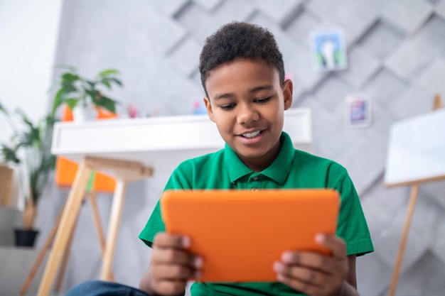Dark-skinned boy looking at tablet with interest