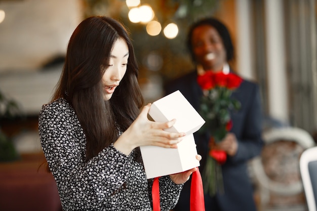 무료 사진 장미와 함께 어두운 피부의 남자. 선물을 가진 행복 한 소녀입니다. 카페에서 낭만적 인 저녁.