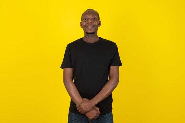 Dark-skinned young man standing and posing on yellow wall