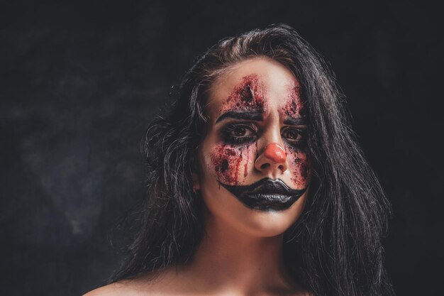 In the dark, smoky photo studio young girl has a photo shoot in a role of creepy clown.