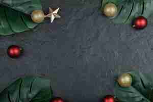 Free photo dark surface with christmas baubles and leaves