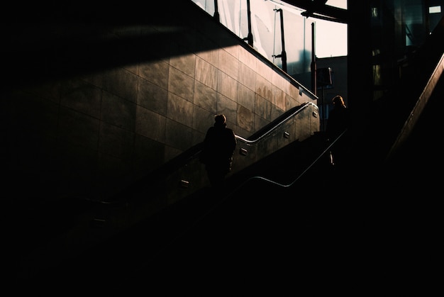 Free photo dark underground area with two people walking down the stairs